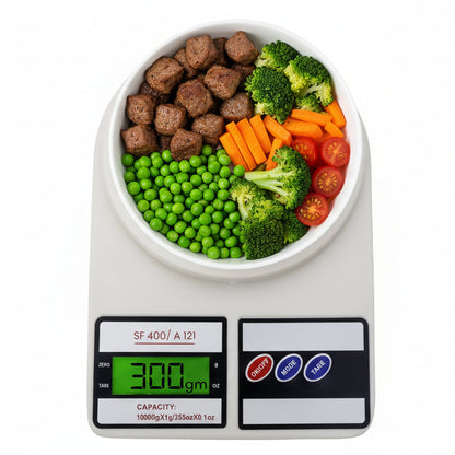 Digital kitchen scale with bowl of peas, broccoli, carrots, tomatoes, and food cubes, 300g